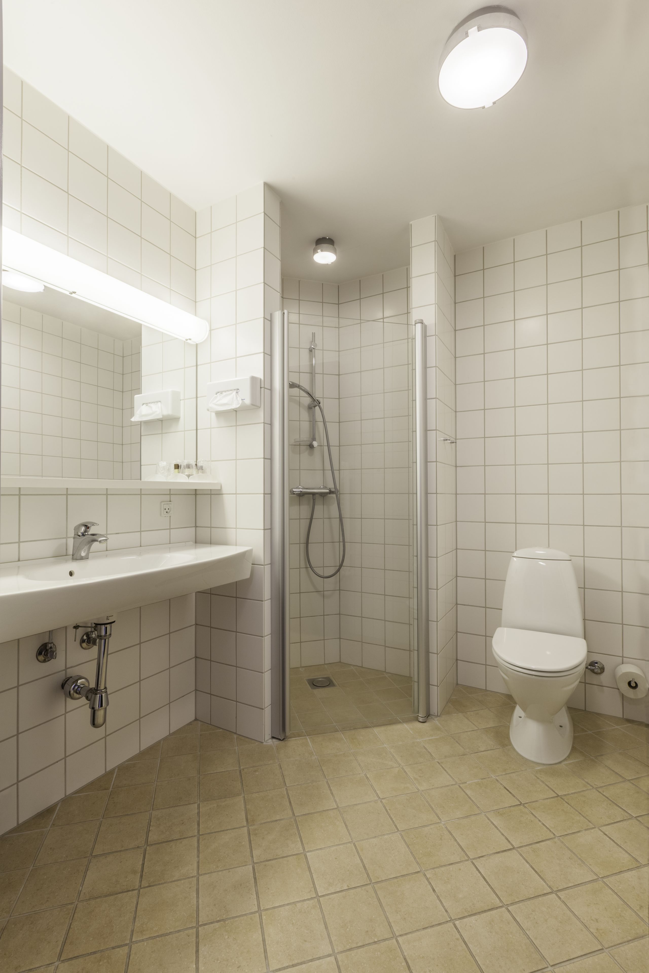 A bathroom with a white sink, mirror, and toilet, and a glass-enclosed shower area.
