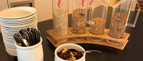 A breakfast setup with multiple bowls of cereal and a bowl of mixed nuts.