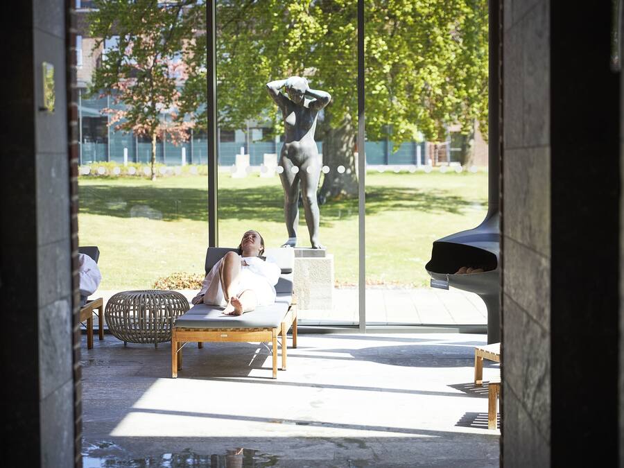 A person relaxing on a lounge chair in an outdoor area with a statue in the background.