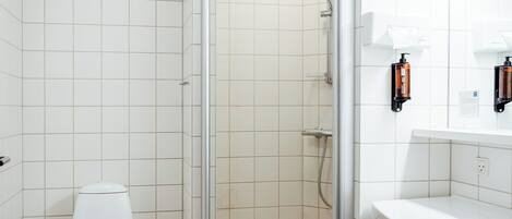 A bathroom with a toilet, shower, and sink.