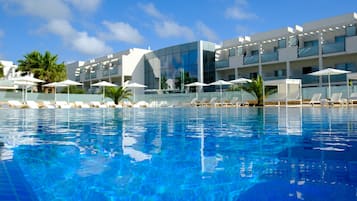 Una piscina al aire libre, sombrillas, sillones reclinables de piscina