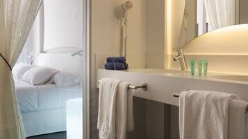 Un baño moderno con un espejo grande, un secador de pelo y un perchero para toallas.