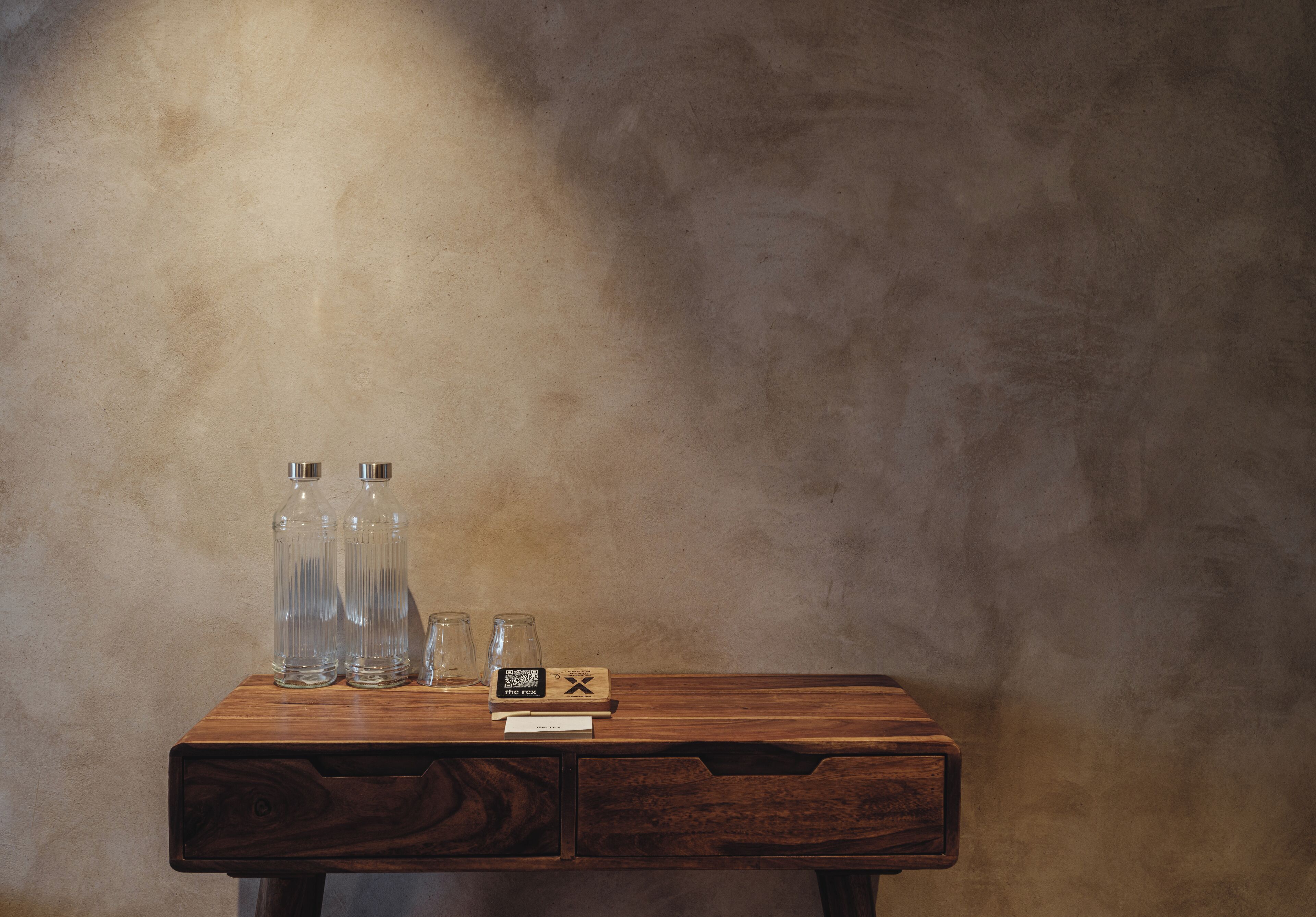 A wooden table with three clear bottles and a QR code.