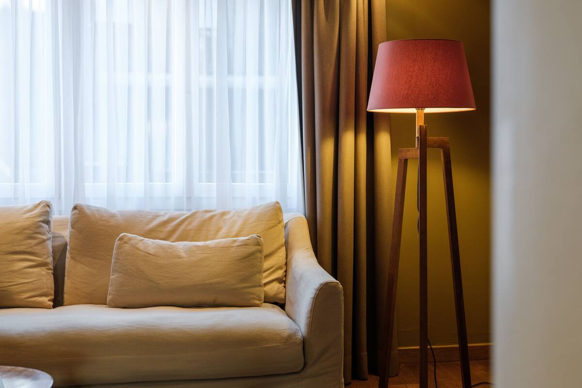A room with a sofa, a floor lamp, and curtains.