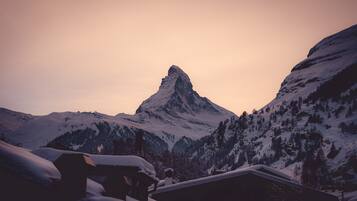 Un paysage de montagne avec un sommet imposant, des pentes enneigées et quelques bâtiments au premier plan.