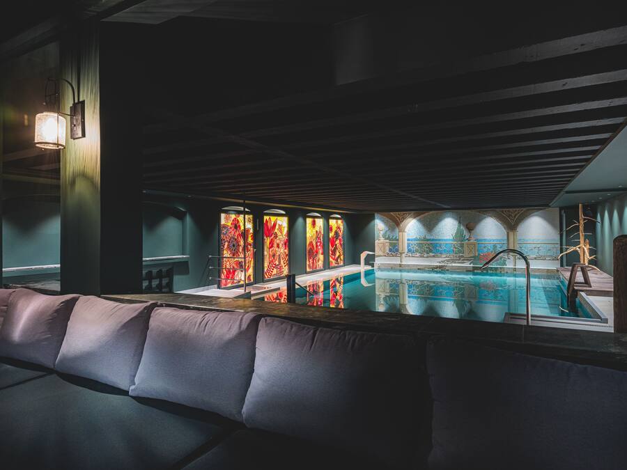 Zona de bar con piscina, asientos acolchados y ventanas de vitral.