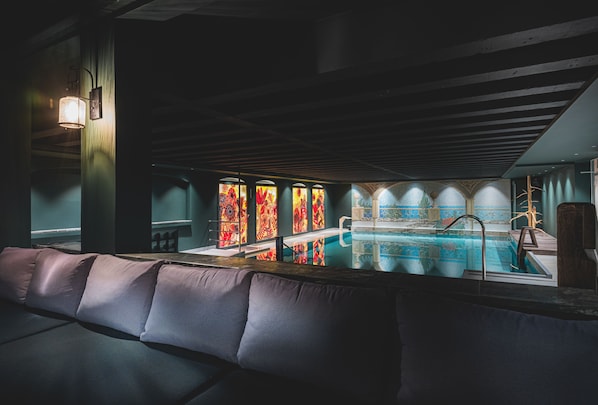 A bar area with a pool, cushioned seating, and stained glass windows.