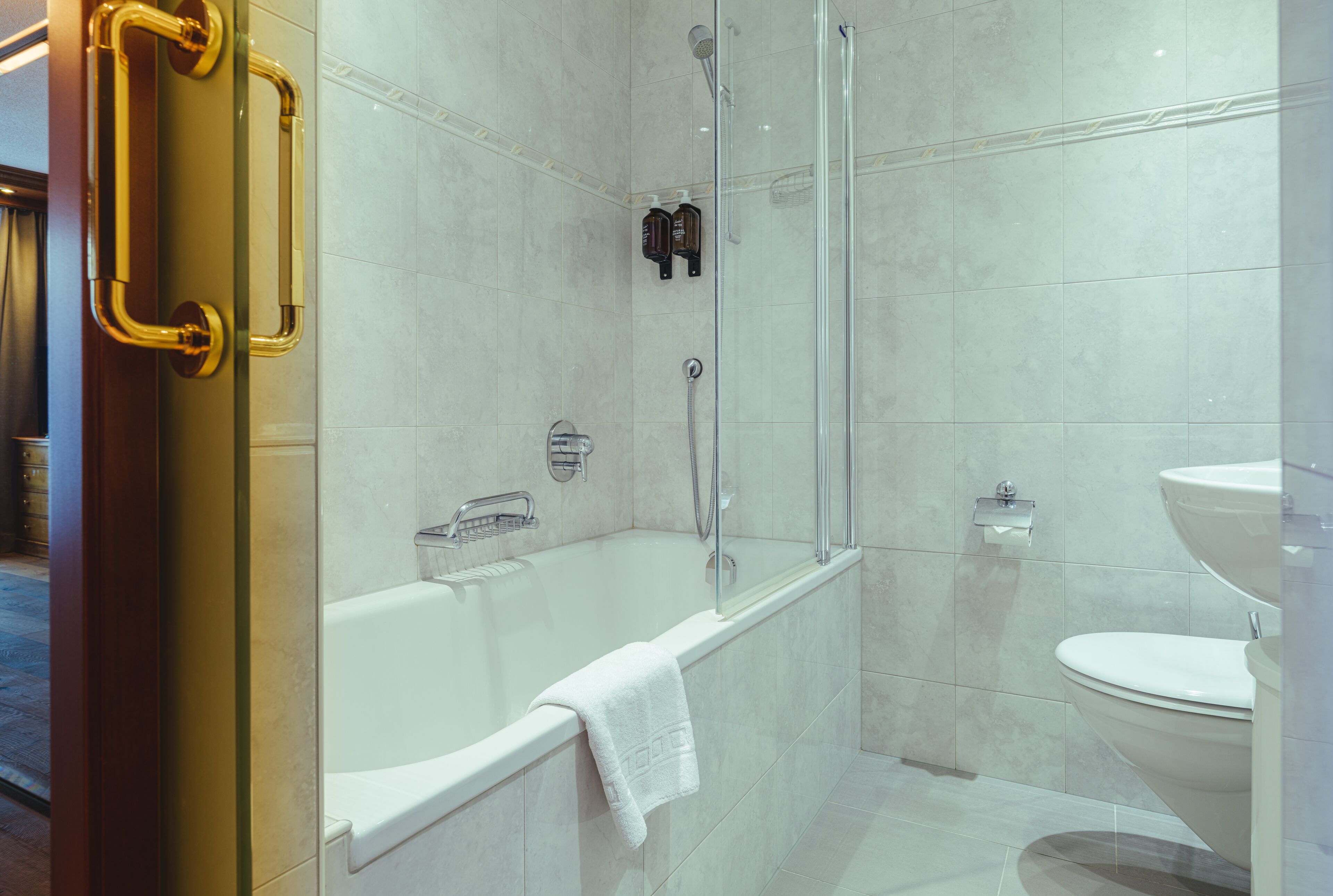 Een moderne badkamer met een bad, douche en toilet.