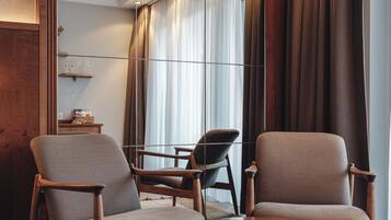 Une pièce moderne avec deux fauteuils, une petite table et un grand miroir.
