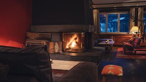 Un salon chaleureux avec une cheminée, des sièges confortables et une vue sur l’extérieur.