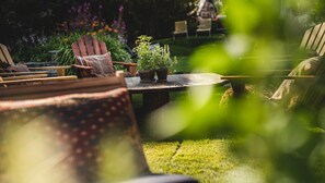 A garden patio with wooden furniture, a round table, and potted plants.
