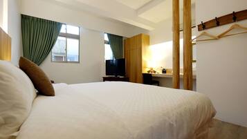 Una habitación de hotel con una cama grande, televisión, escritorio con silla y armario.