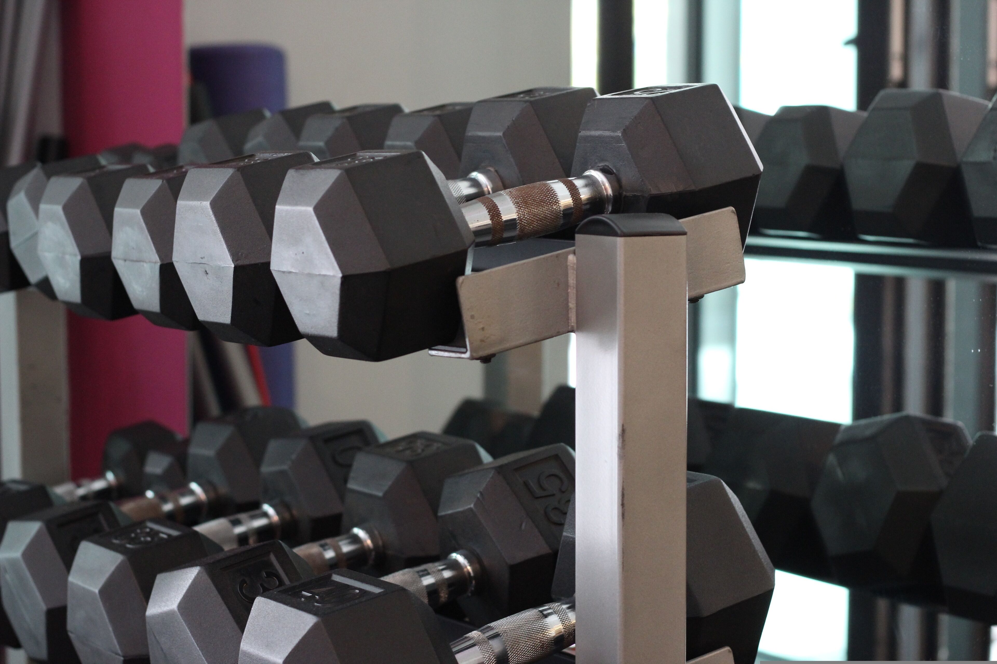 Et stativ med sekskantede håndvægte med vægtangivelser, der signalerer et fitnesscenter.