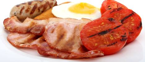 Un plato con tocino, salchichas, un huevo frito y tomates a la parrilla.