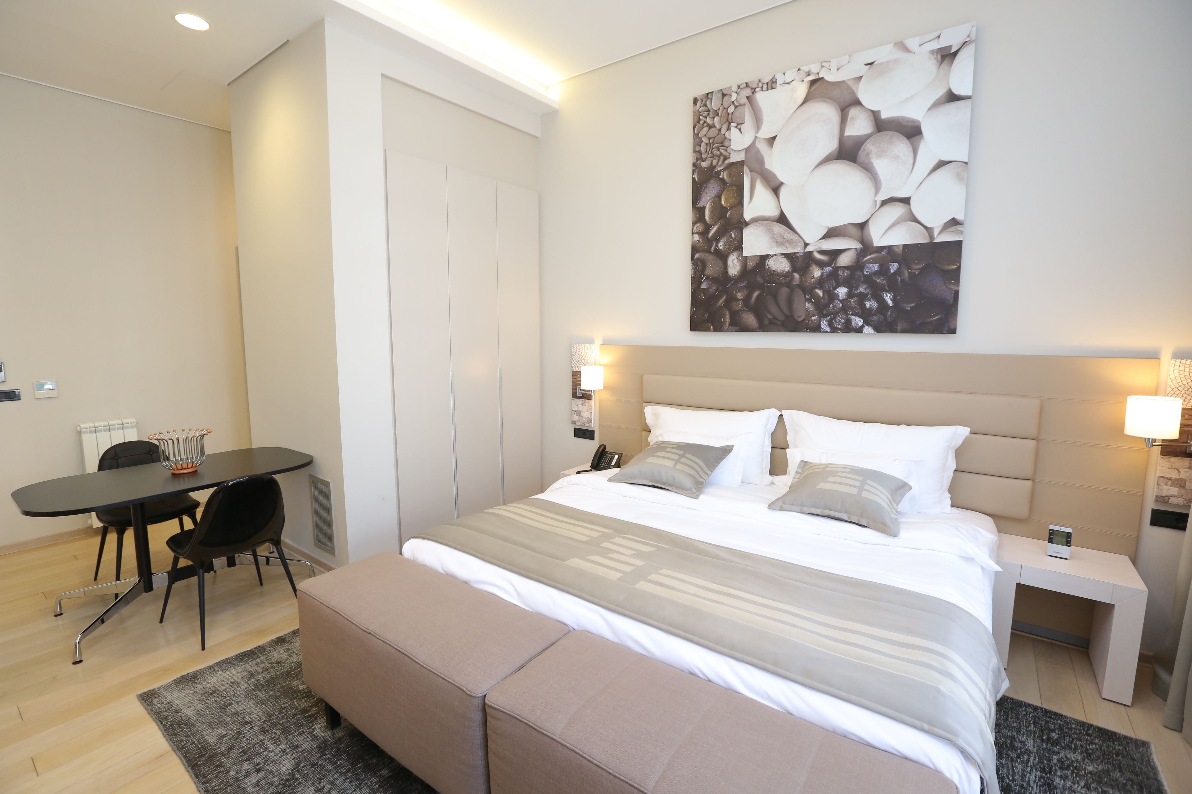 A modern bedroom with a large bed, bedside tables, a desk, and a chair.