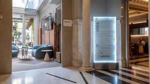 A hotel lobby with a reception desk, seating area, and a digital directory.