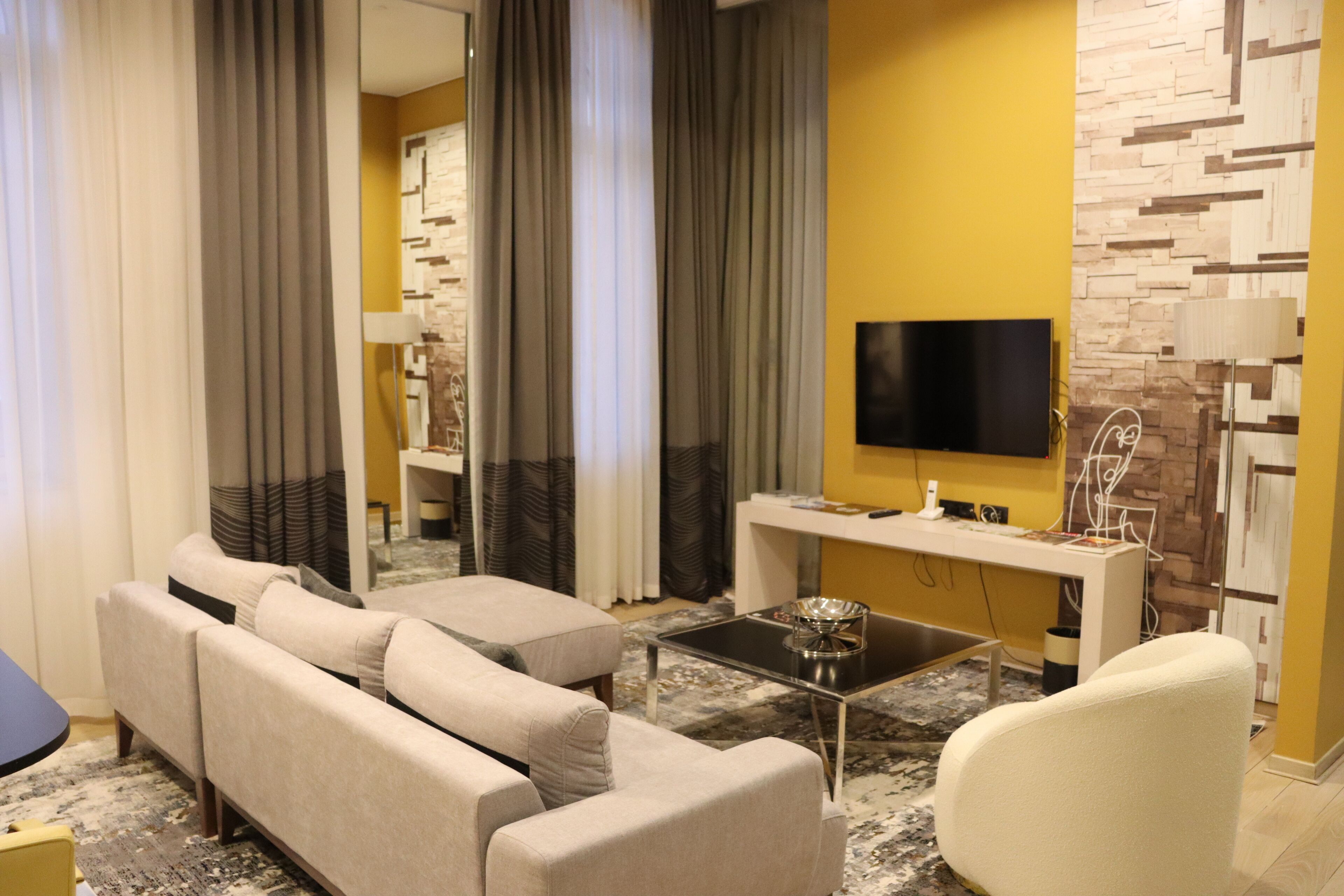 Una sala de estar moderna con un sofá, un sillón, una mesa de centro y un televisor de pantalla plana montado en la pared.