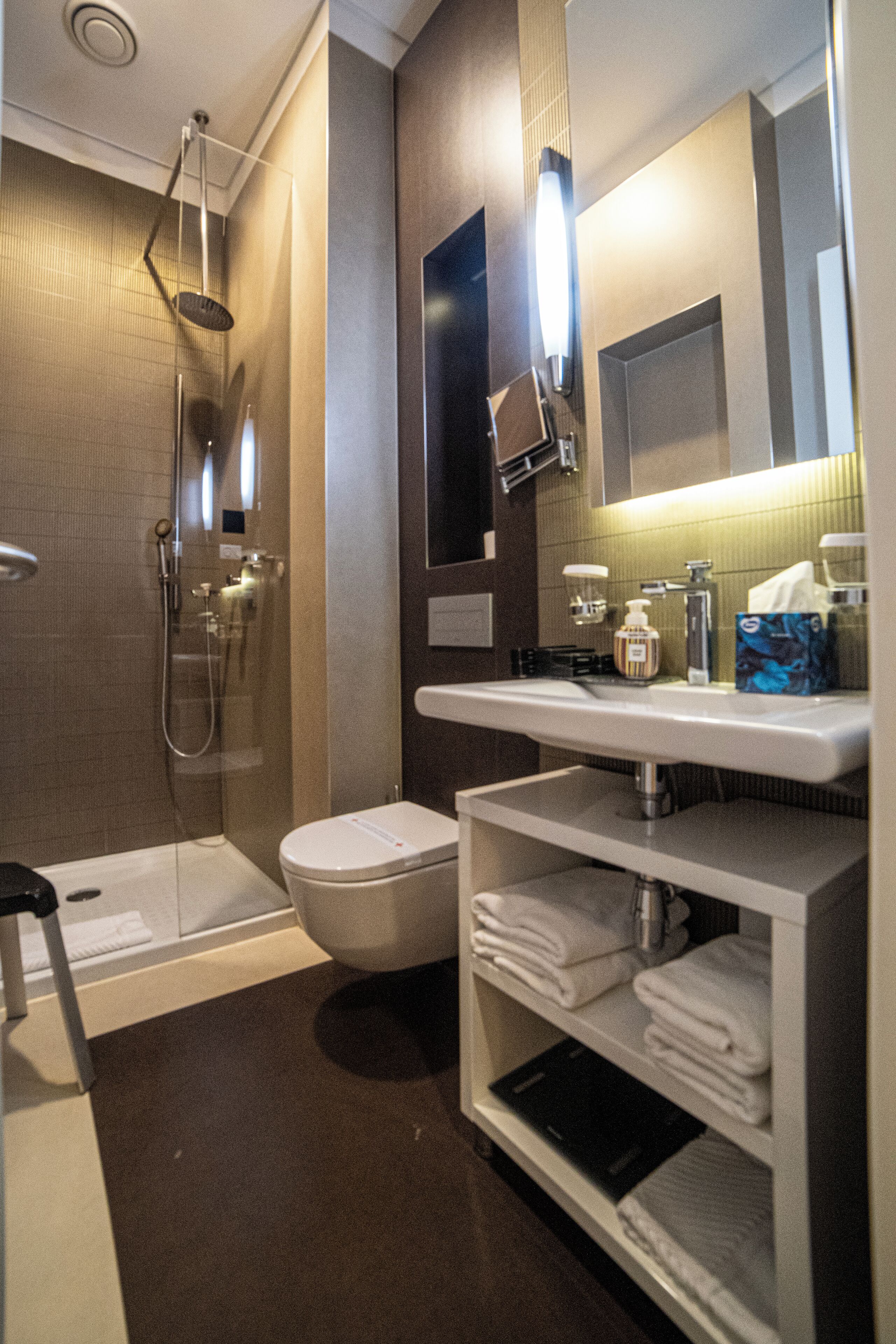 A modern bathroom with a shower, toilet, and sink.