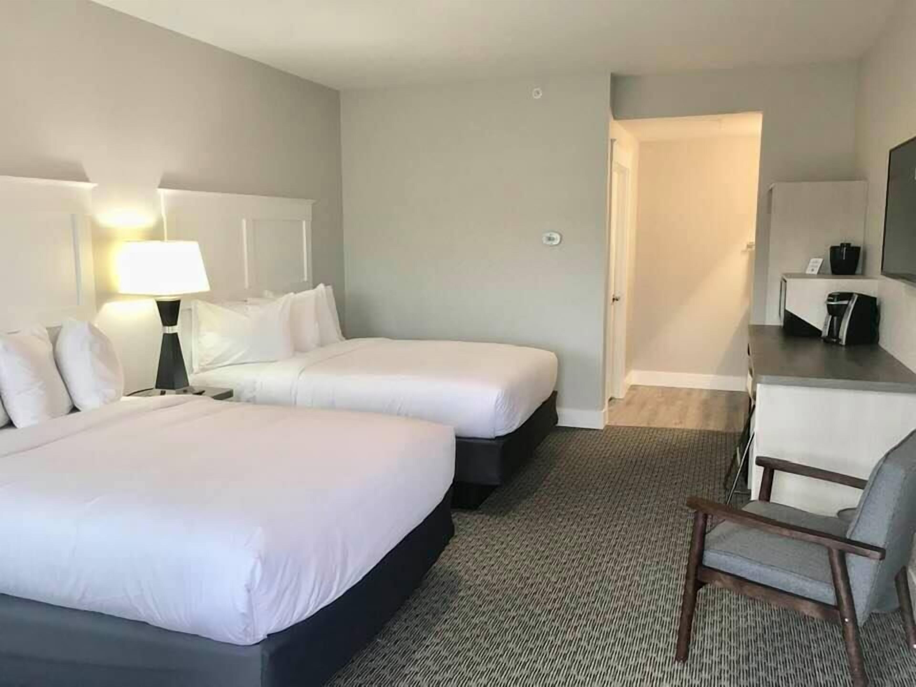 Een hotelkamer met twee bedden, een bureau, een stoel en een televisie.