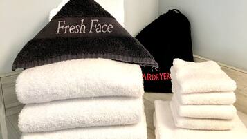 A stack of white towels with a black towel on top labeled "Fresh Face" and a black bag with "AIRDRYER" text.