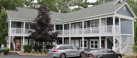 A two-story building with a covered front porch and a staircase leading to the upper level.