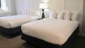Habitación de hotel con dos camas, una mesita de noche, una lámpara y una ventana.