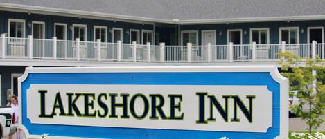 Letrero del Lakeshore Inn con un esquema de color azul y blanco, rodeado de flores blancas.