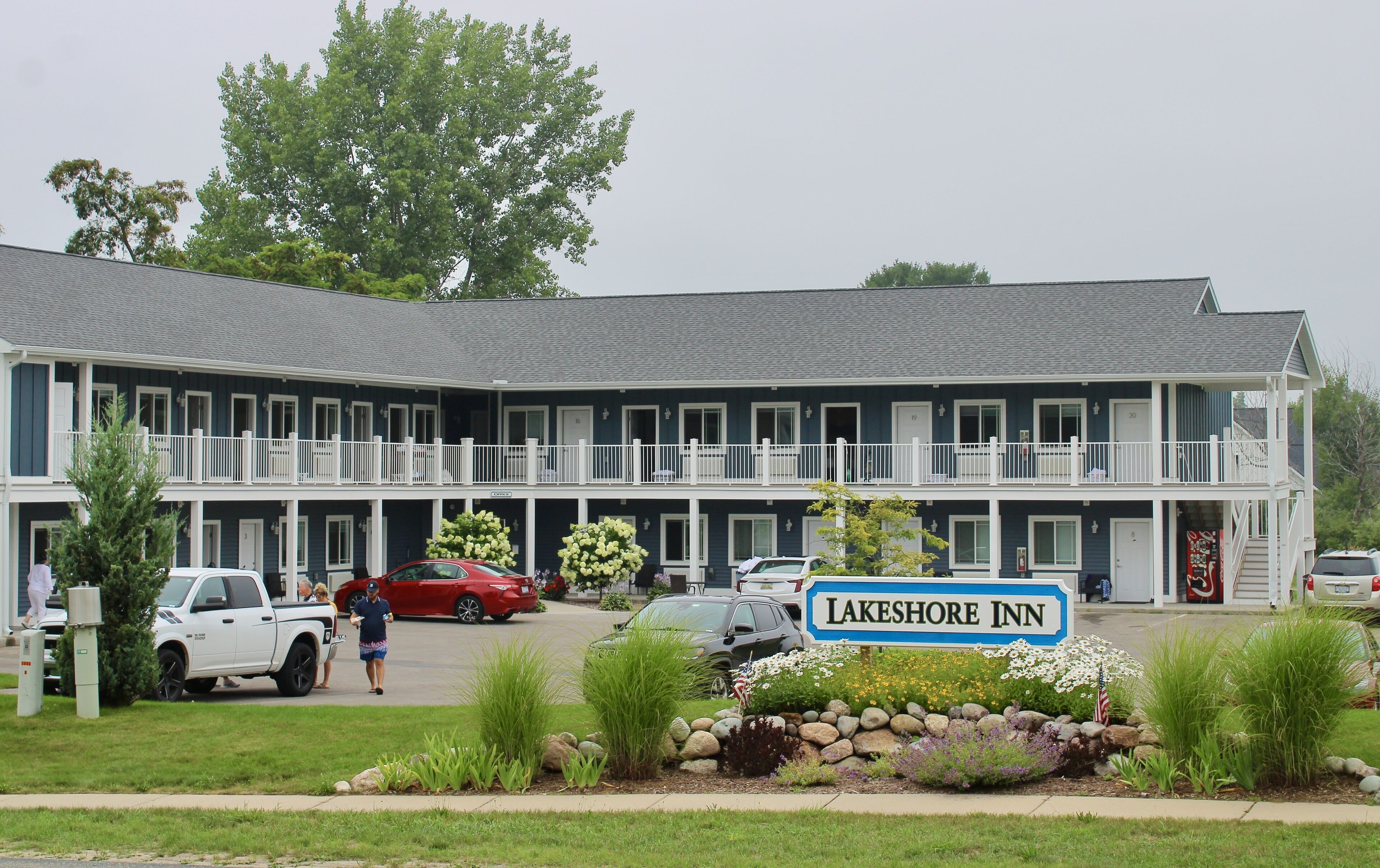 A two-story Lakeshore Inn with a balcony on each floor, a parking lot, and a landscaped front garden.