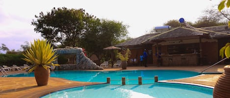 Una piscina al aire libre, sombrillas, sillones reclinables de piscina