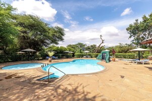 Una piscina al aire libre, sombrillas, sillones reclinables de piscina