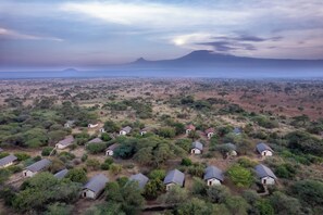 An aerial view of a rural settlement with scattered houses, surrounded by sparse vegetation and a distant mountain.