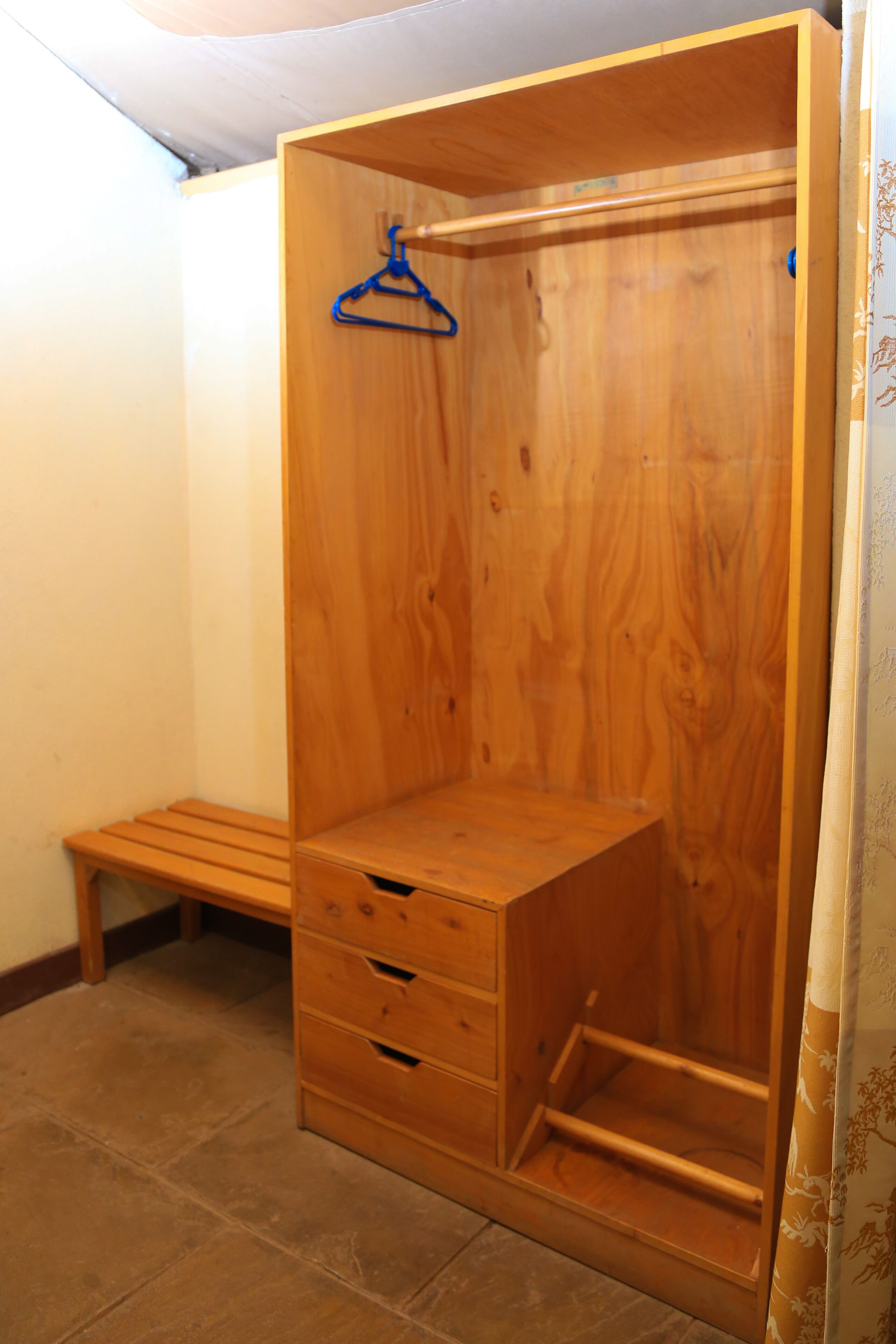 Une armoire en bois avec une tringle pour suspendre les vêtements et des tiroirs.