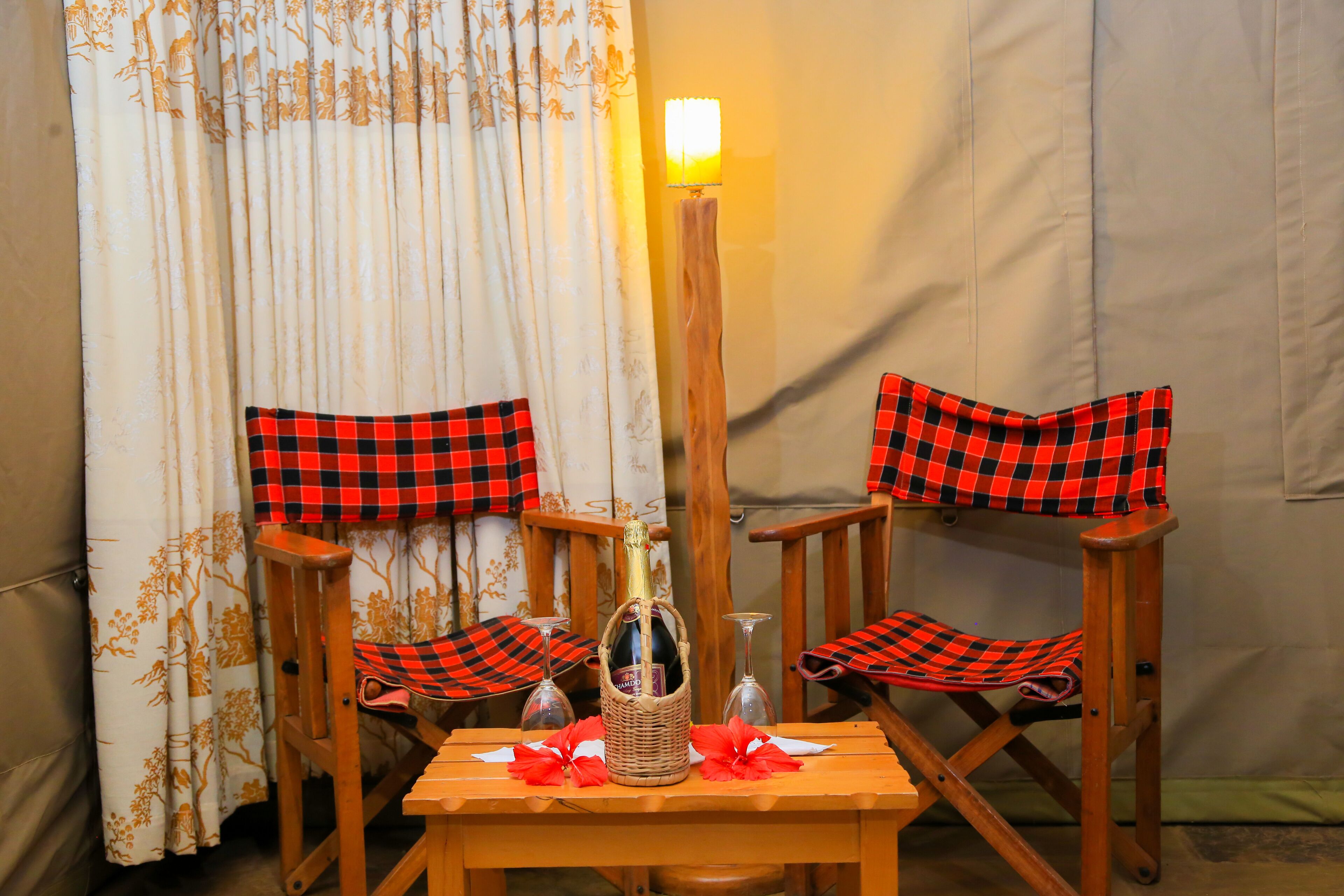 A table with a bottle and glasses, flanked by two chairs with checkered cushions.
