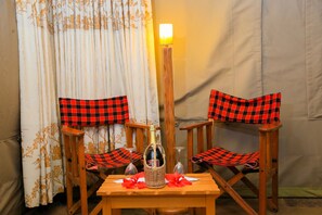 A table with a bottle and glasses, flanked by two chairs with checkered cushions.