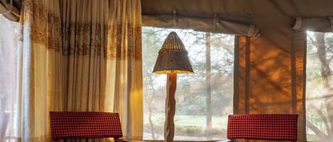 A cozy room with two checkered chairs, a small table, and a unique conical lamp.