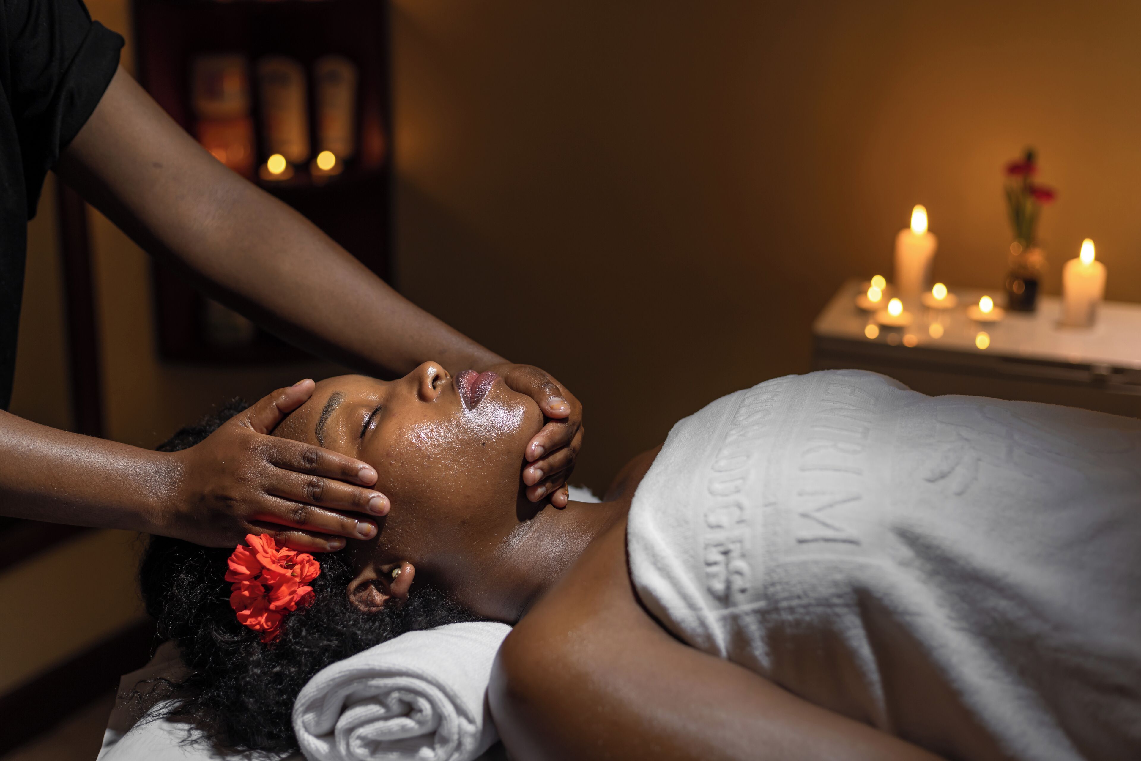 A person receiving a massage in a dimly lit room with candles on a table.