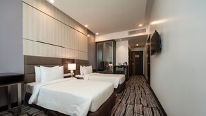 Een hotelkamer met twee bedden, een bureau, een televisie en een spiegel.