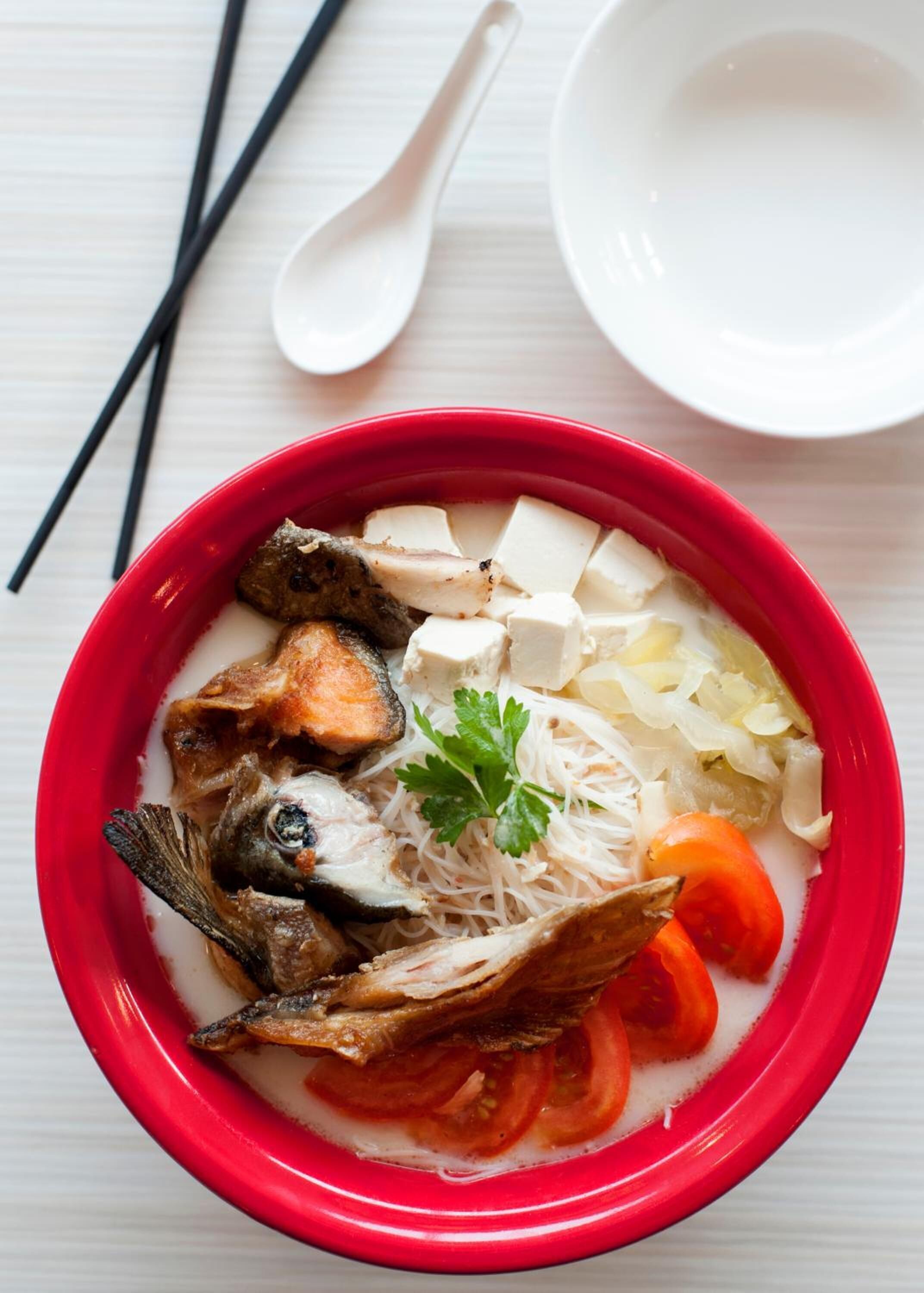En skål soppa med olika ingredienser, till exempel fisk, tofu och grönsaker.