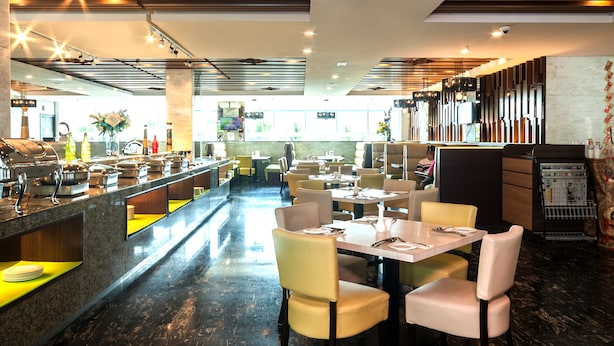 Een modern restaurant met een lange toonbank, meerdere tafels en een marmeren vloer.