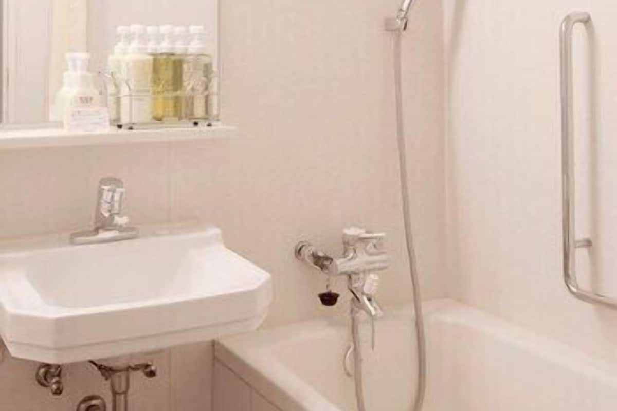 A bathroom with a sink, mirror, and shower.