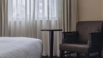 A hotel room with a bed, a chair, and a small table.