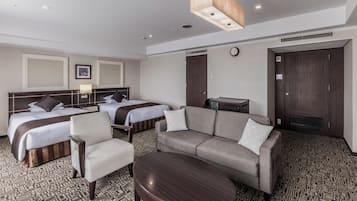 A hotel room with two beds, a sofa, a chair, a small table, and a clock on the wall.