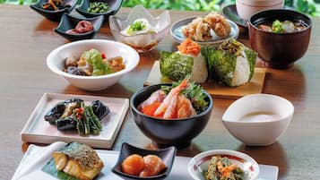 A variety of Japanese dishes arranged on a wooden table with a garden view in the background.