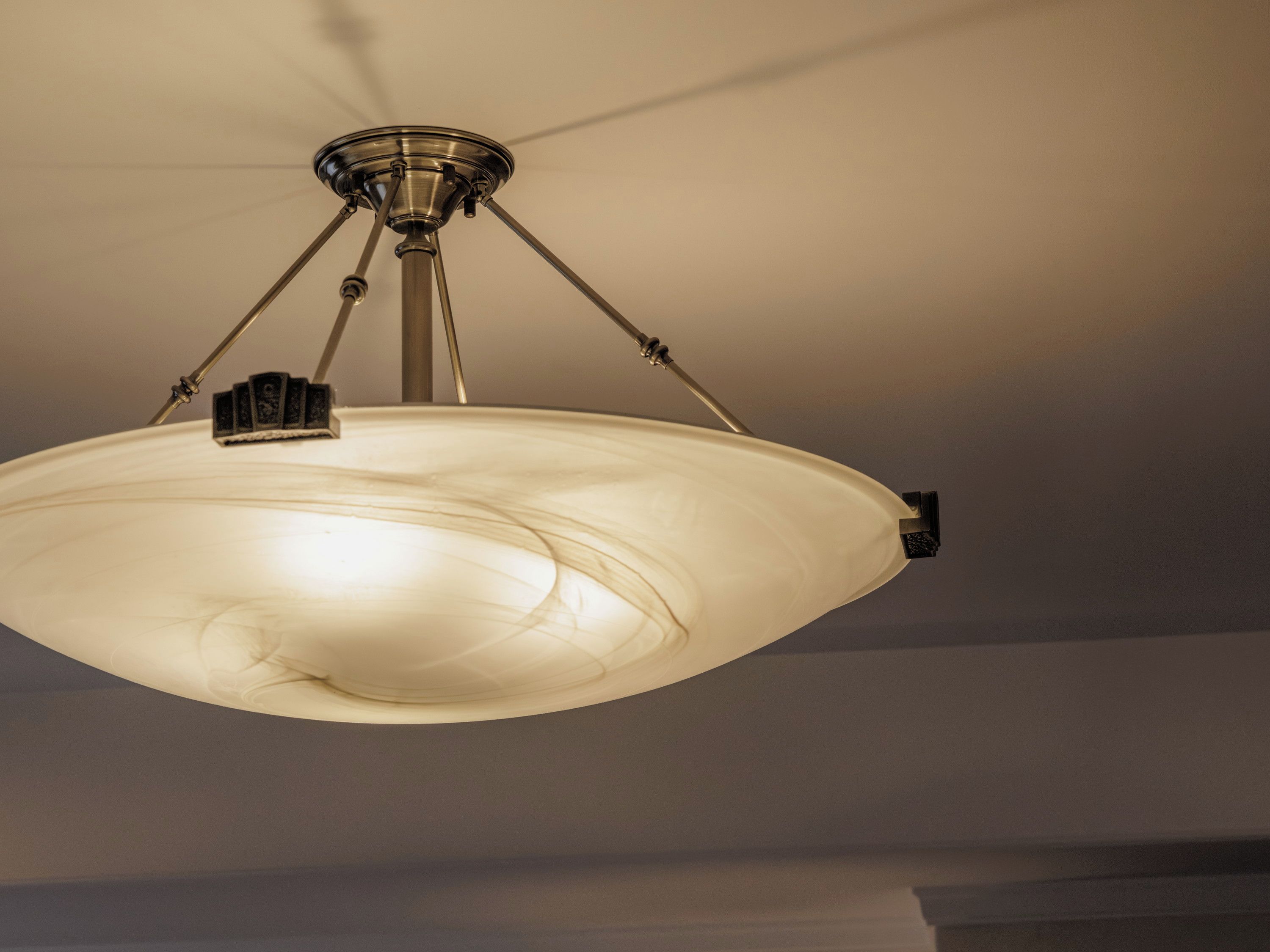 A ceiling-mounted light fixture with a central shade and three adjustable arms.