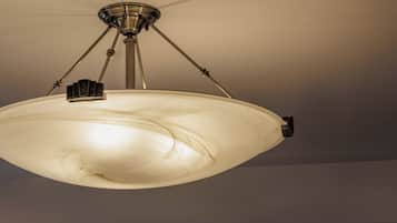 A ceiling-mounted light fixture with a central shade and three adjustable arms.