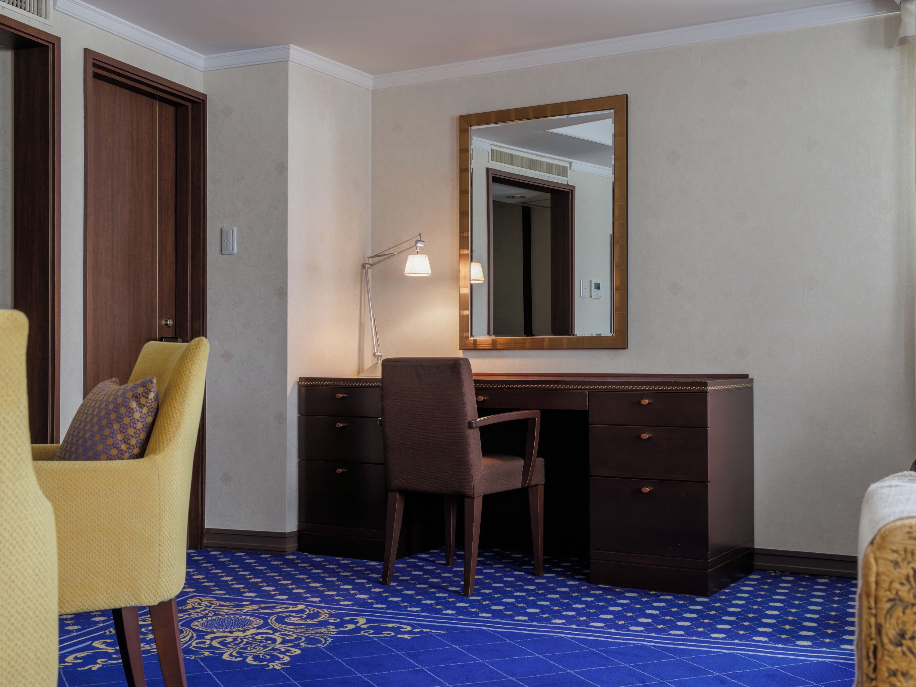 Ein Hotelzimmer mit Schreibtisch, Stuhl und einem großen Spiegel.