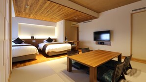 Una habitación de hotel con dos camas, una mesa de comedor de madera y un televisor montado en la pared.