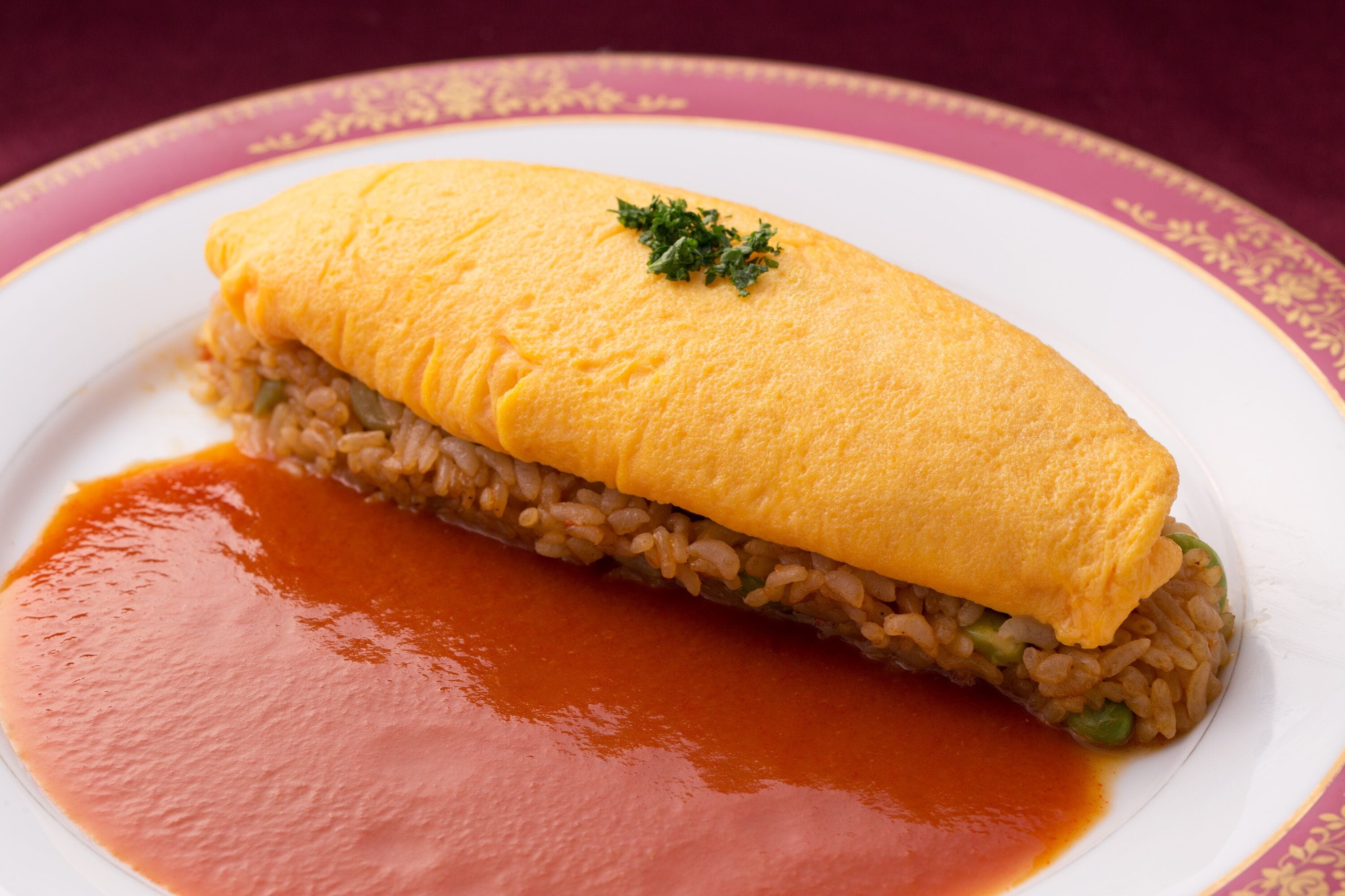 A plate with a rolled omelette, rice, and sauce.