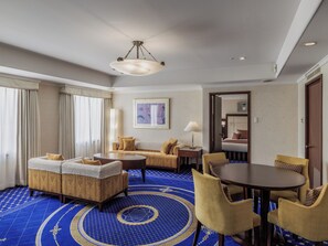 A hotel room with a large bed, a sofa, a dining table, and a patterned carpet. - Nishitetsu Grand Hotel (Fukuoka)