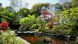 A serene garden with a pond, lush greenery, and flowering plants. - Nishitetsu Grand Hotel (Fukuoka)